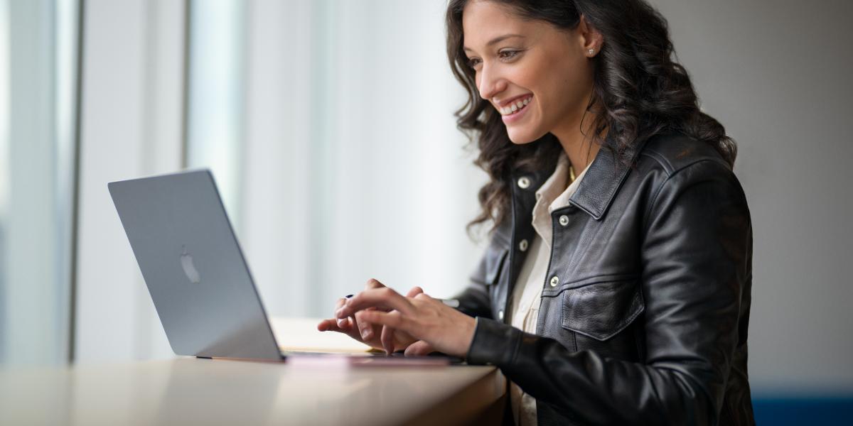 Die Mitarbeiterin einer Bildungseinrichtung arbeitet auf ihrem MacBook