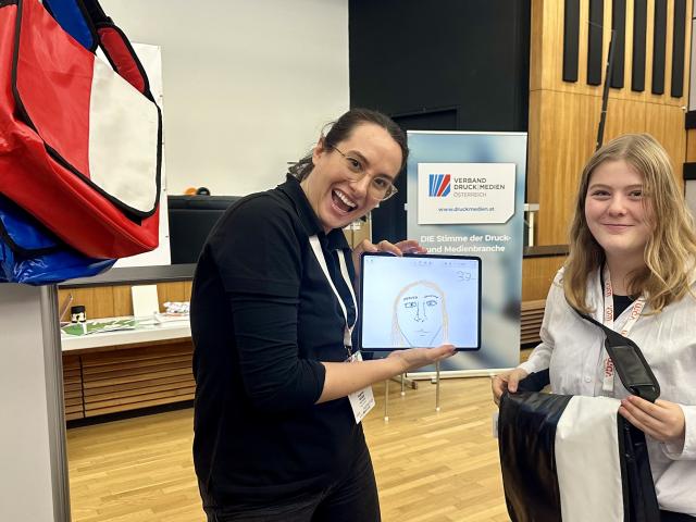 Sophia Khan von Tools at Work Apple Education Team mit einer Gewinnerin beim Stand auf der Print Fair